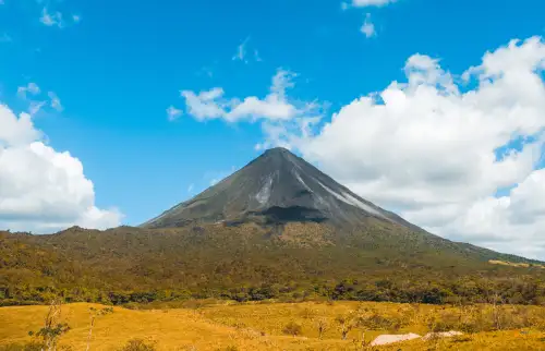 Arenal Volcano in La Fortuna Costa Rica - Far away view over a field and then the rainforest at the base of the volcano