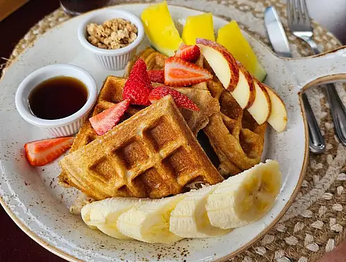 Delicious healthy breakfast with waffles, banana, apples & strawberry at Harmony Organic Food in La Fortuna Costa Rica