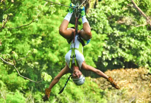 smiling woman upside down on the Los Suenos zipline canopy tour in Costa Rica